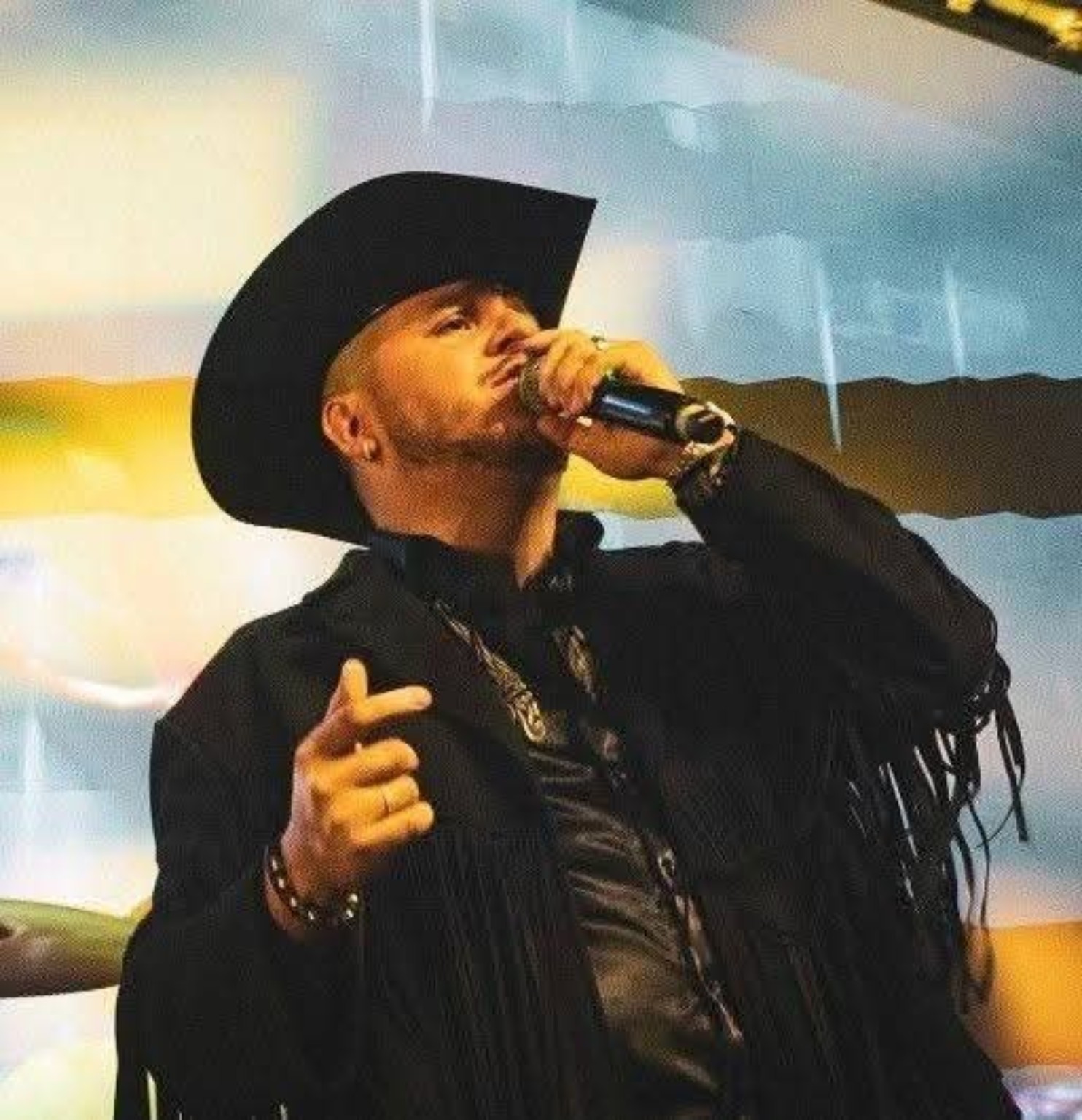 Franco el Tenor cantando con micrófono y sombrero negro