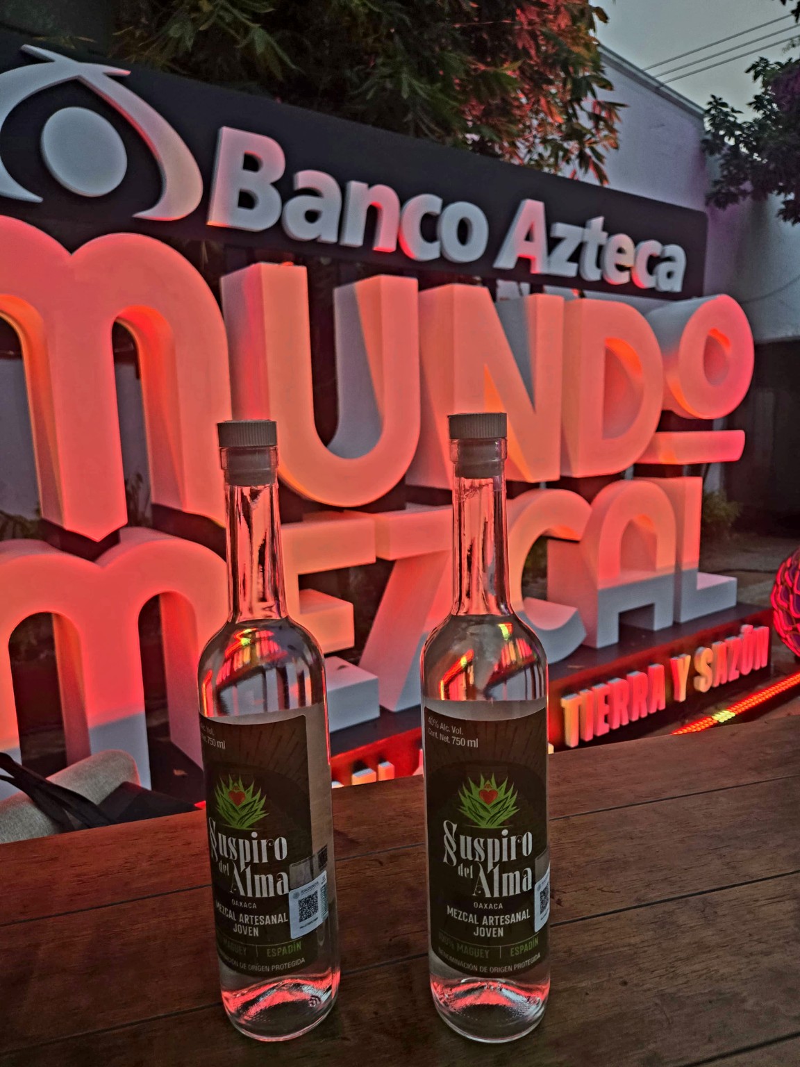 Dos botellas originales de Suspiro del Alma frente al aviso de Mundo Mezcal