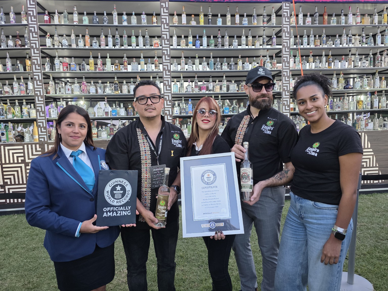 Equipo y botella de Suspiro del Alma junto al certificado de Mundo Mezcal y la representante de Guinness World Records